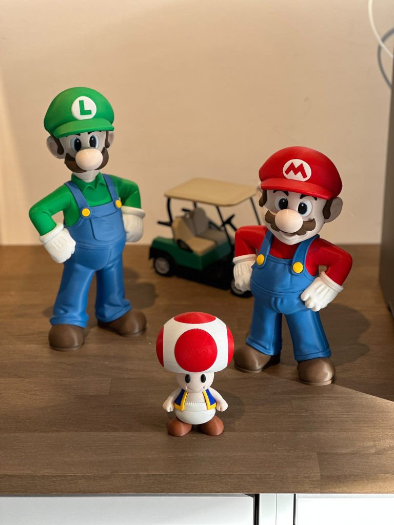 Drie geprinte figuren met een geprint golfkarretje op de achtergrond