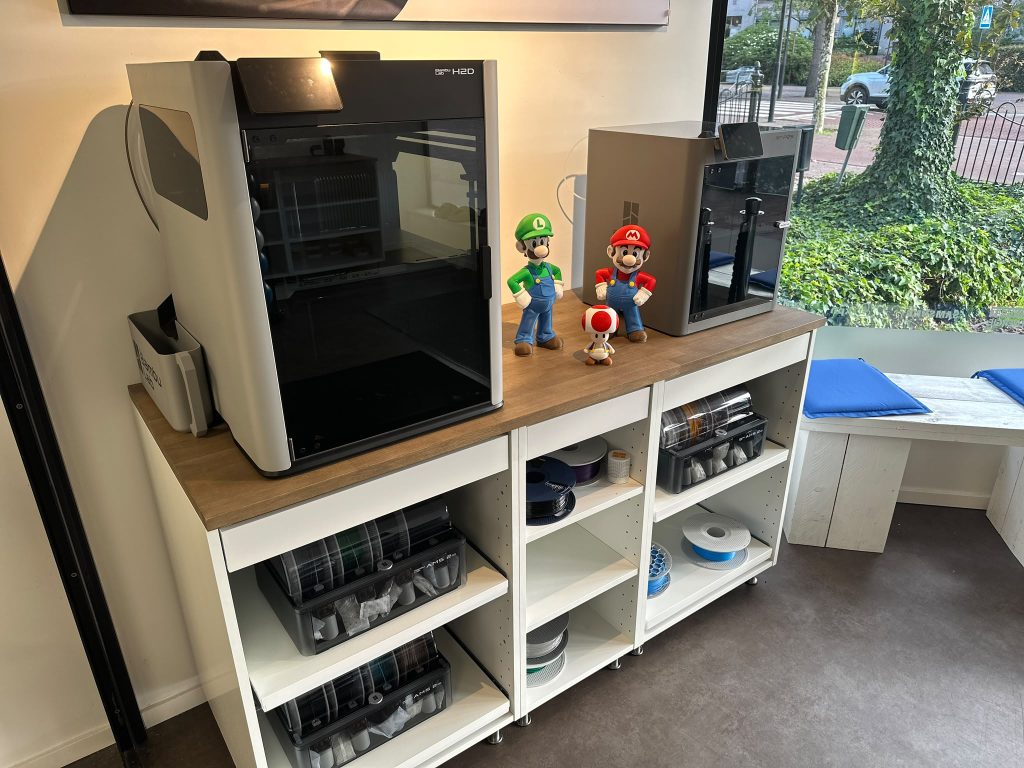 Bambu Lab-printers op een kast met filament en geprinte figuren