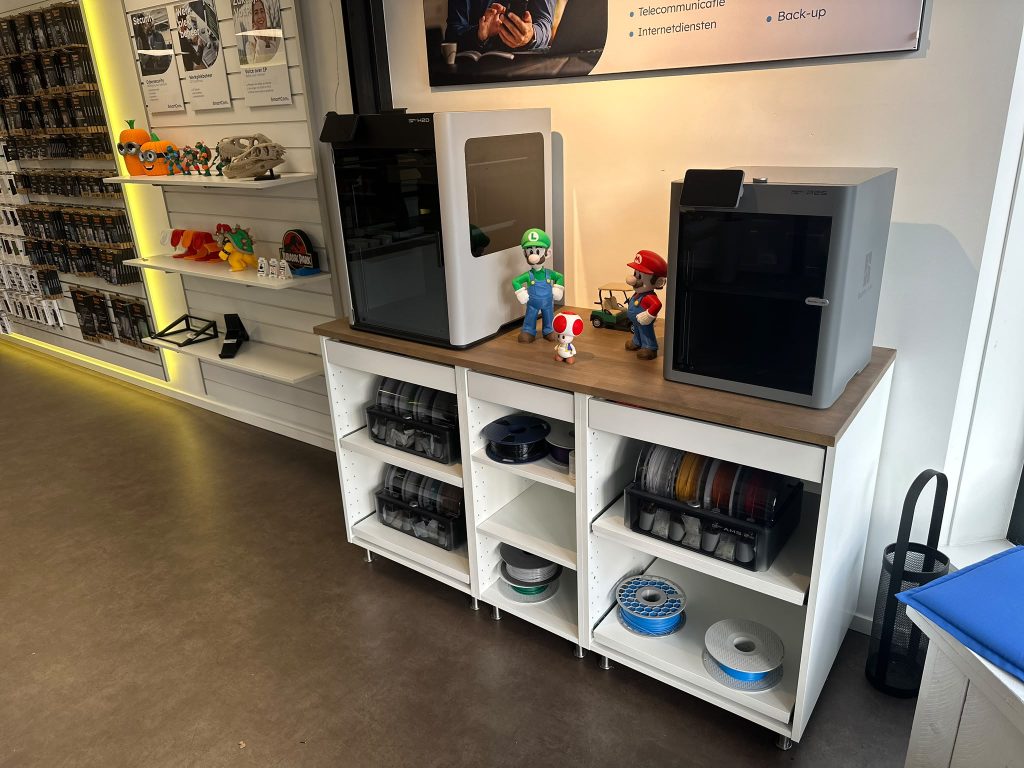 Showroom met Bambu Lab-printers en kasten vol filament
